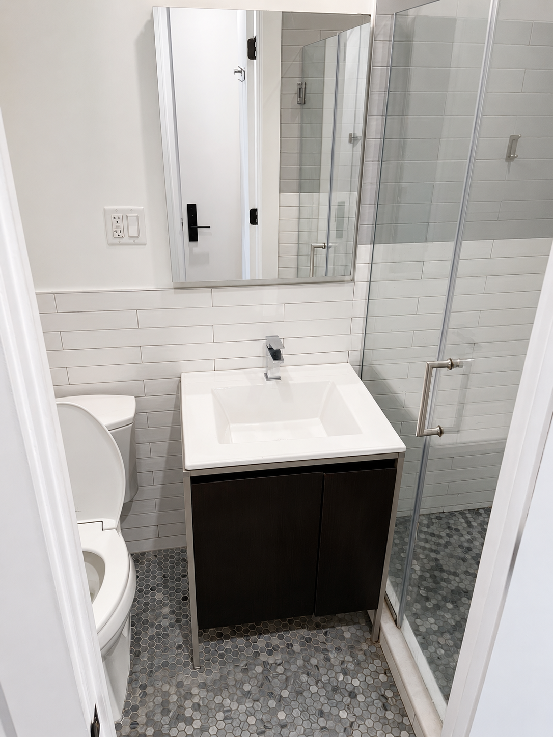 After: finished bathroom with glass shower and dark vanity